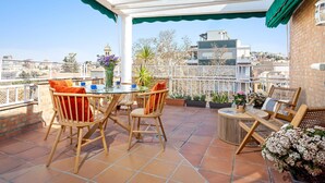 Una terrassa amb una taula, cadires i plantes en testos.