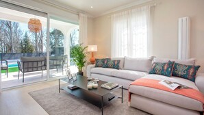 A modern living room with a sofa, coffee table, and a view of the outdoors.
