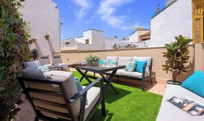 An outdoor patio with a sofa, chairs, and a table, surrounded by greenery and a clear sky. - Genteel Home Rodrigo Caro (Seville)