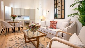 A modern living room with a sofa, chairs, a coffee table, and a kitchen in the background. - Genteel Home Rodrigo Caro (Seville)