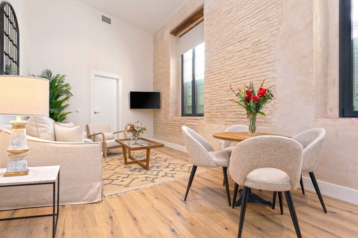 A modern living room with a sofa, chairs, a coffee table, and a TV mounted on the wall.