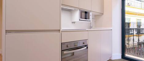 A modern kitchen with white cabinets, a built-in microwave, and an oven.
