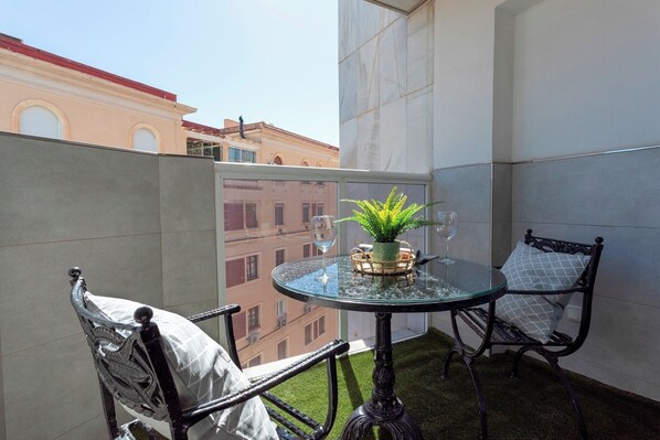 A small balcony with a glass table, two chairs, a potted plant, and a wine glass. - Genteel Home Duquesa de Parcent (Málaga)