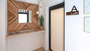 A modern interior with a wooden herringbone wall, a mirror, a hanging light fixture, a potted plant, and a door labeled "A Loft". - Genteel Home La Paz (Granada)