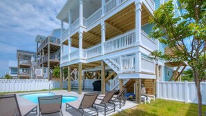 Un immeuble à plusieurs étages doté de balcons, d’une piscine et d’un espace extérieur aménagé pour s’asseoir.