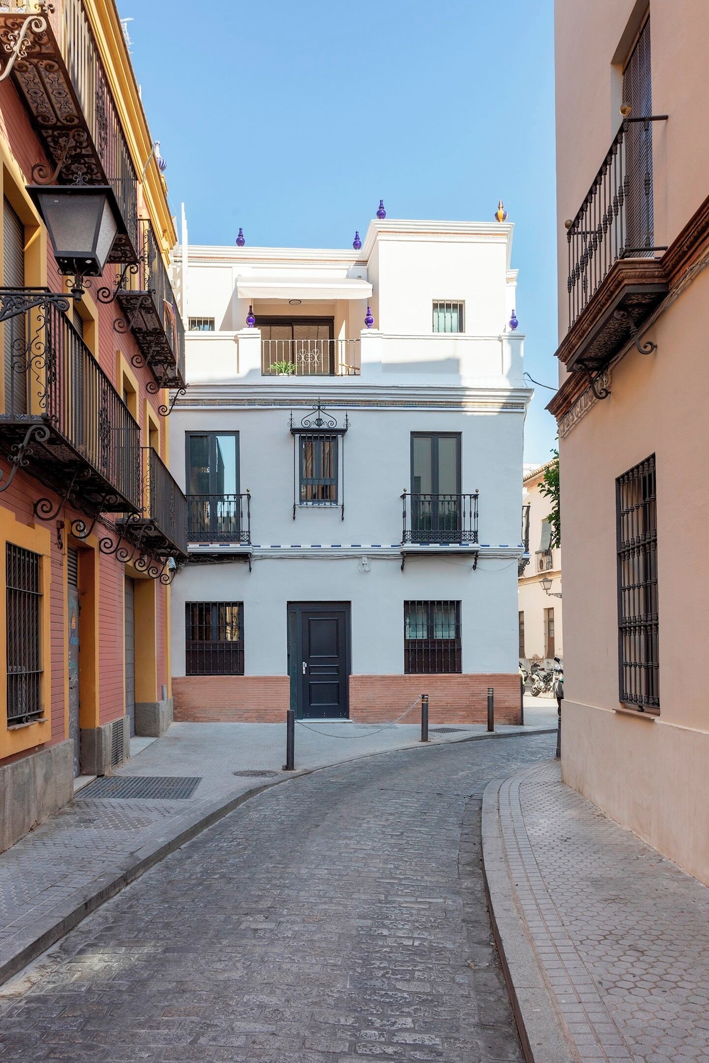 Una estrecha calle adoquinada flanqueada por edificios con balcones y una puerta central.
