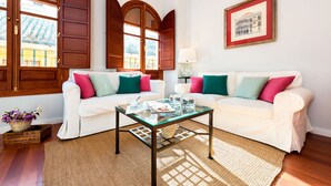 A living room with two white sofas, colorful cushions, a glass coffee table, a woven rug, and a framed picture on the wall. - Genteel Home Plaza Nueva (Seville)