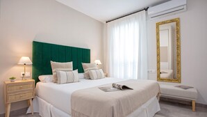 A neatly arranged bedroom with a large bed, bedside tables, a bench, and a mirror. - Genteel Home Santa Marta Córdoba (Córdoba)