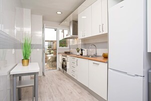 Una cocina moderna con armarios blancos, una campana extractora de acero inoxidable y un horno empotrado.