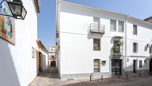 A narrow cobblestone street flanked by white buildings with balconies, a street lamp, and a mural on the left wall. - Genteel Home Santa Marta Córdoba (Córdoba)