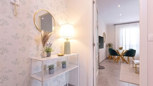 A modern living room with a white console table, a round mirror, and a lamp. There is a dining area with a table and chairs. - Genteel Home Santa Marta Córdoba (Córdoba)