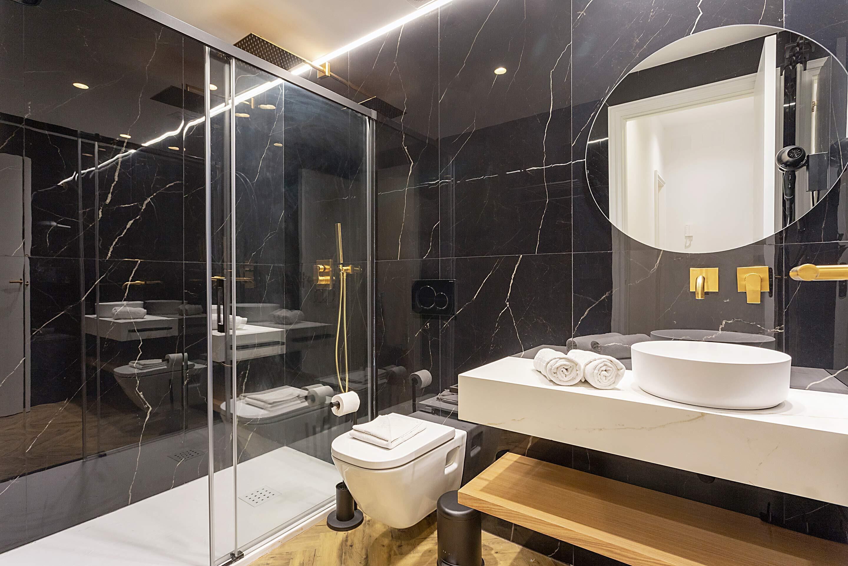 A modern bathroom with a glass-enclosed shower, a white sink, and a large mirror.