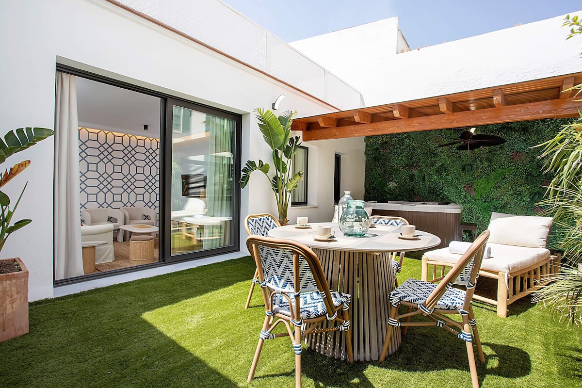 A modern outdoor patio with a round table, wicker chairs, and a glass-enclosed dining area.