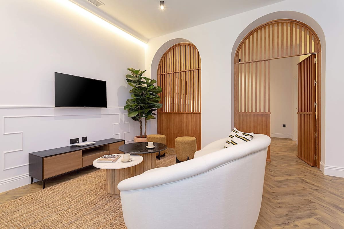 A modern living room with a flat-screen TV, a sofa, a coffee table, and a potted plant.