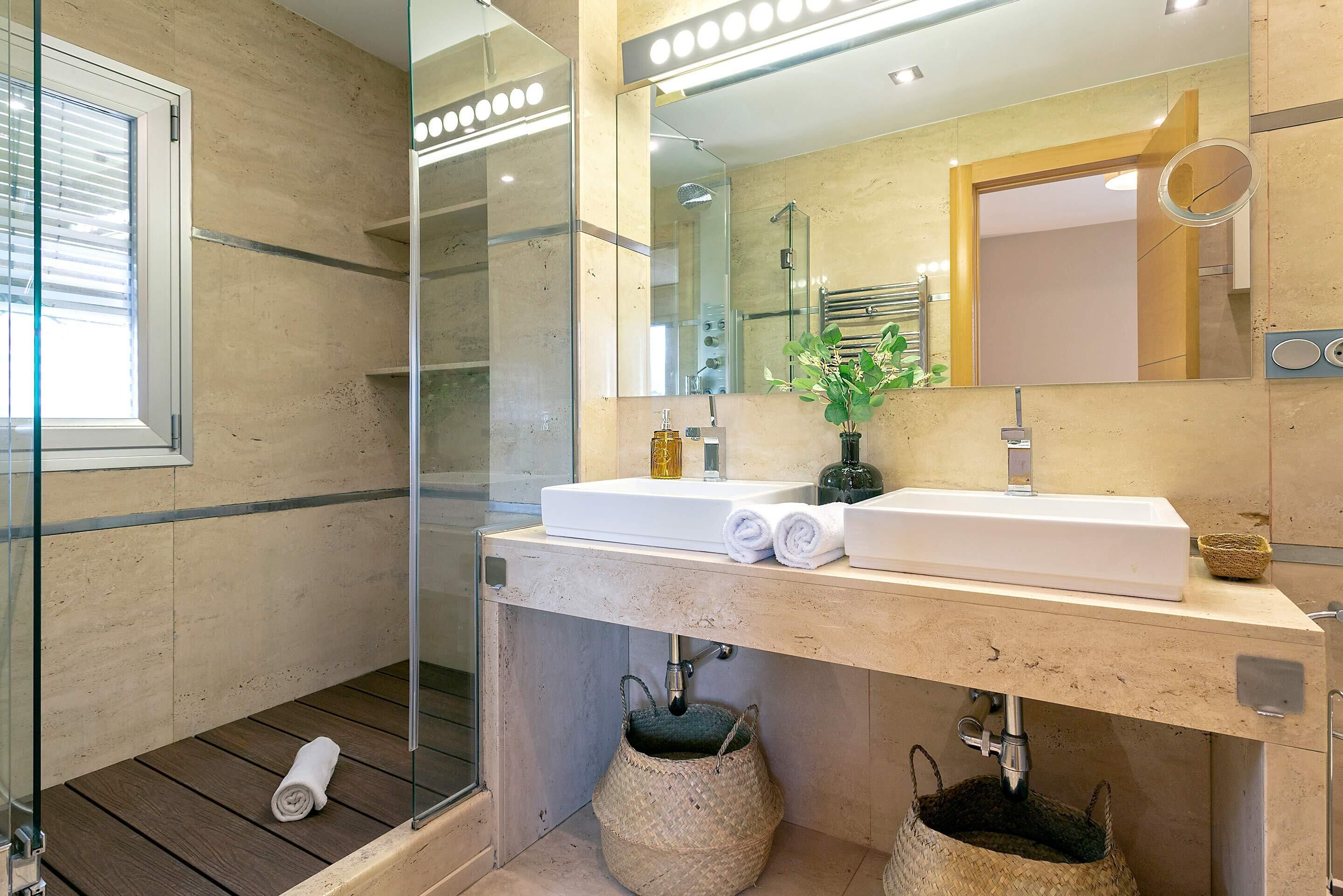 Une salle de bain moderne avec une douche à l’italienne en verre, un lavabo blanc et un grand miroir.
