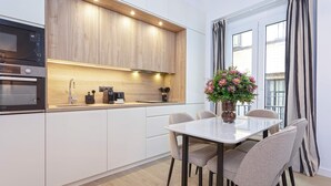 A modern kitchen with wooden cabinets, a built-in oven, and a dining area with a white table and four chairs. - Genteel Home Teodosio (Seville)