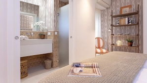 A modern bedroom with a large bed, a bedside table, a mirror, a wardrobe, and a shelf with decorative items. - Genteel Home Plaza del Teatro (Málaga)