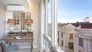A modern room with a desk, two lamps, a chair, and a large window with a city view. - Genteel Home Plaza del Teatro (Málaga)