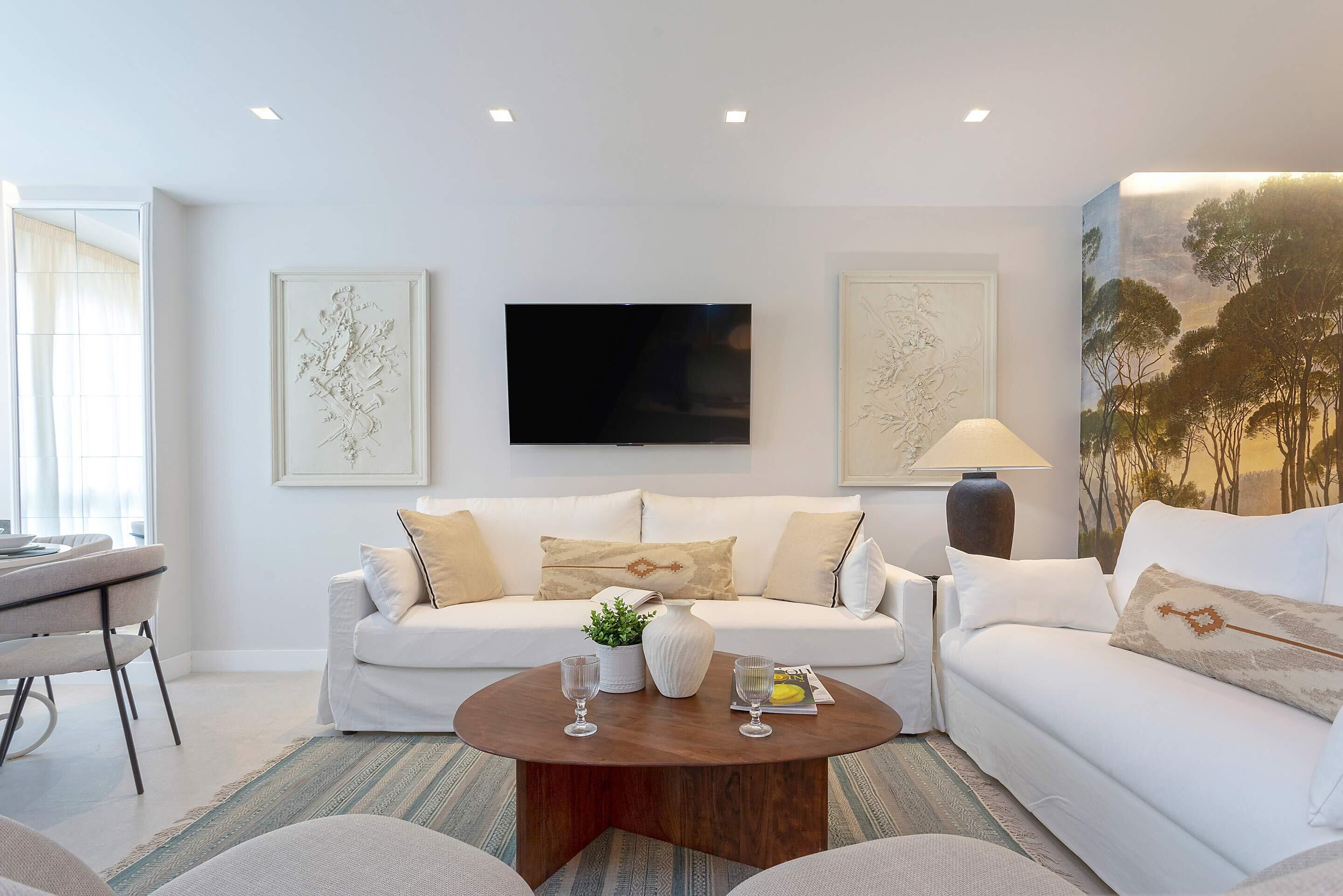 Una sala de estar moderna con un sofá blanco, una mesa de centro y obras de arte en las paredes.
