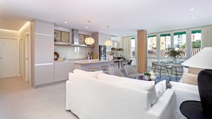 A modern living room with a white sofa, a dining area with a round table, and a kitchen with a central island. - Genteel Home Plaza del Teatro (Málaga)