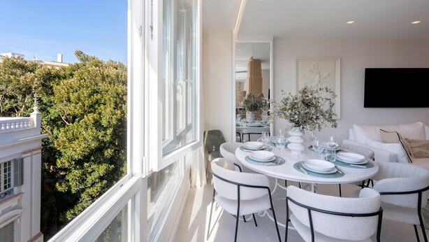 A modern dining area with a round table set for six, white chairs, and a vase of flowers. - Genteel Home Plaza del Teatro (Málaga)