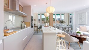 A modern kitchen with a central island, a dining area with a view, and a living space with a sofa and coffee table. - Genteel Home Plaza del Teatro (Málaga)
