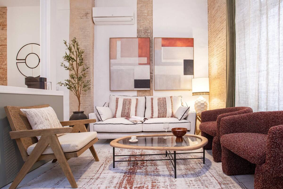 Un salon moderne avec un canapé blanc, des fauteuils en bois et une table basse en verre.