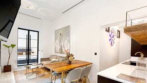 A modern kitchen with a wooden dining table, grey chairs, and a white countertop. - Genteel Home Placentines (Seville)