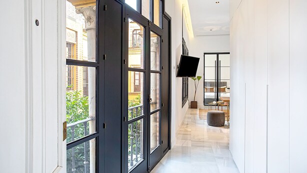A hallway with large windows, a flat-screen TV, and a modern interior design. - Genteel Home Placentines (Seville)