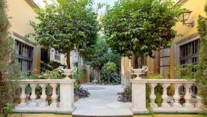 A courtyard with a fountain, surrounded by yellow walls and trees. - Genteel Home Placentines (Seville)