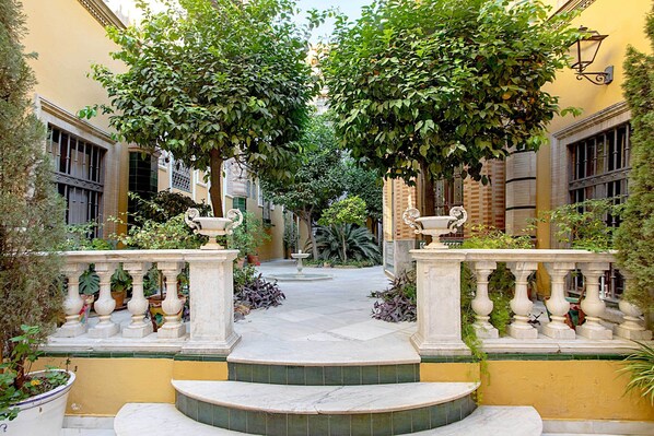 A courtyard with a fountain, surrounded by yellow walls and trees. - Genteel Home Placentines (Seville)