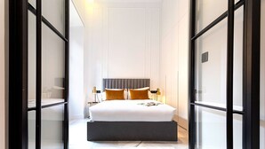 A modern hotel room with a large bed, a bedside table, and a nightstand. - Genteel Home Placentines (Seville)