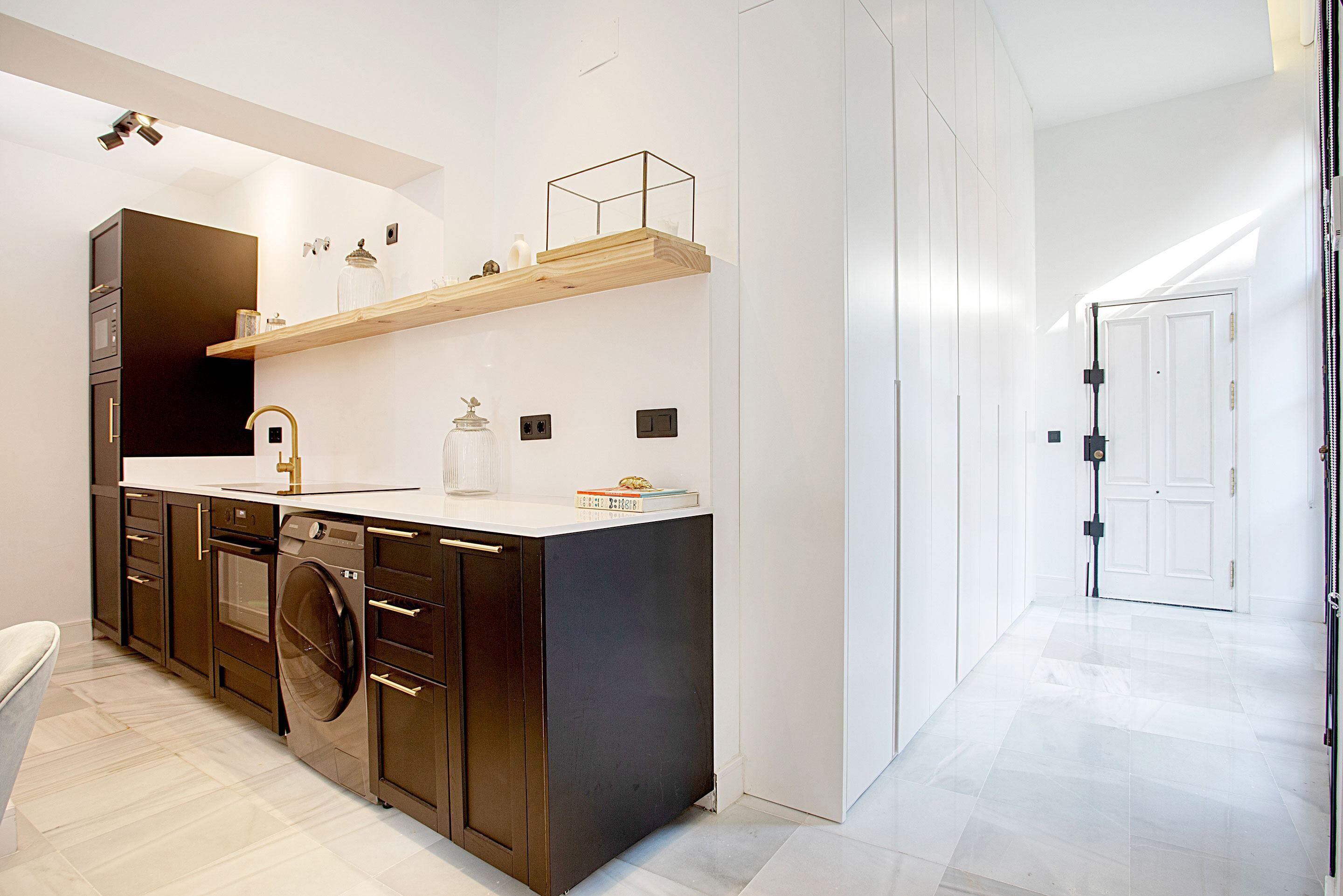 A modern kitchen with dark cabinetry, a stainless steel sink, and a built-in washing machine.