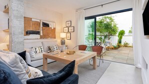 A modern living room with a sofa, coffee table, and chairs. There is a large window with a view of greenery outside. - Genteel Home Pureza (Seville)