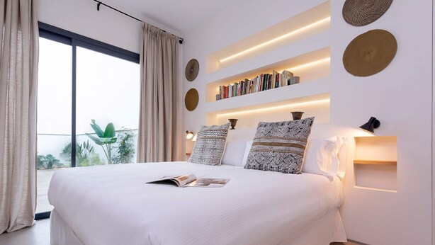A modern bedroom with a large bed, bookshelves, and a view of greenery. - Genteel Home Pureza (Seville)