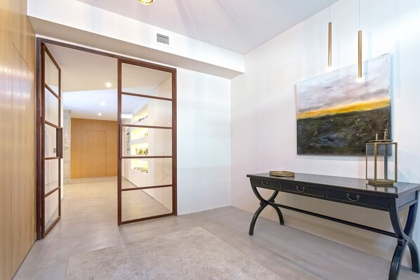 A modern interior with a sliding door leading to a room, a desk with drawers, and a painting on the wall. - Genteel Home Pureza (Seville)