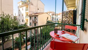 A balcony with a red table and chairs, a book, and a cup. - Genteel Home Vittorio Emanuele (Florence)