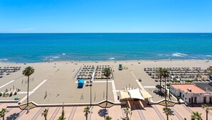 Une plage dotée d’un parking, de parasols et d’un bâtiment portant l’inscription « Riviera ».