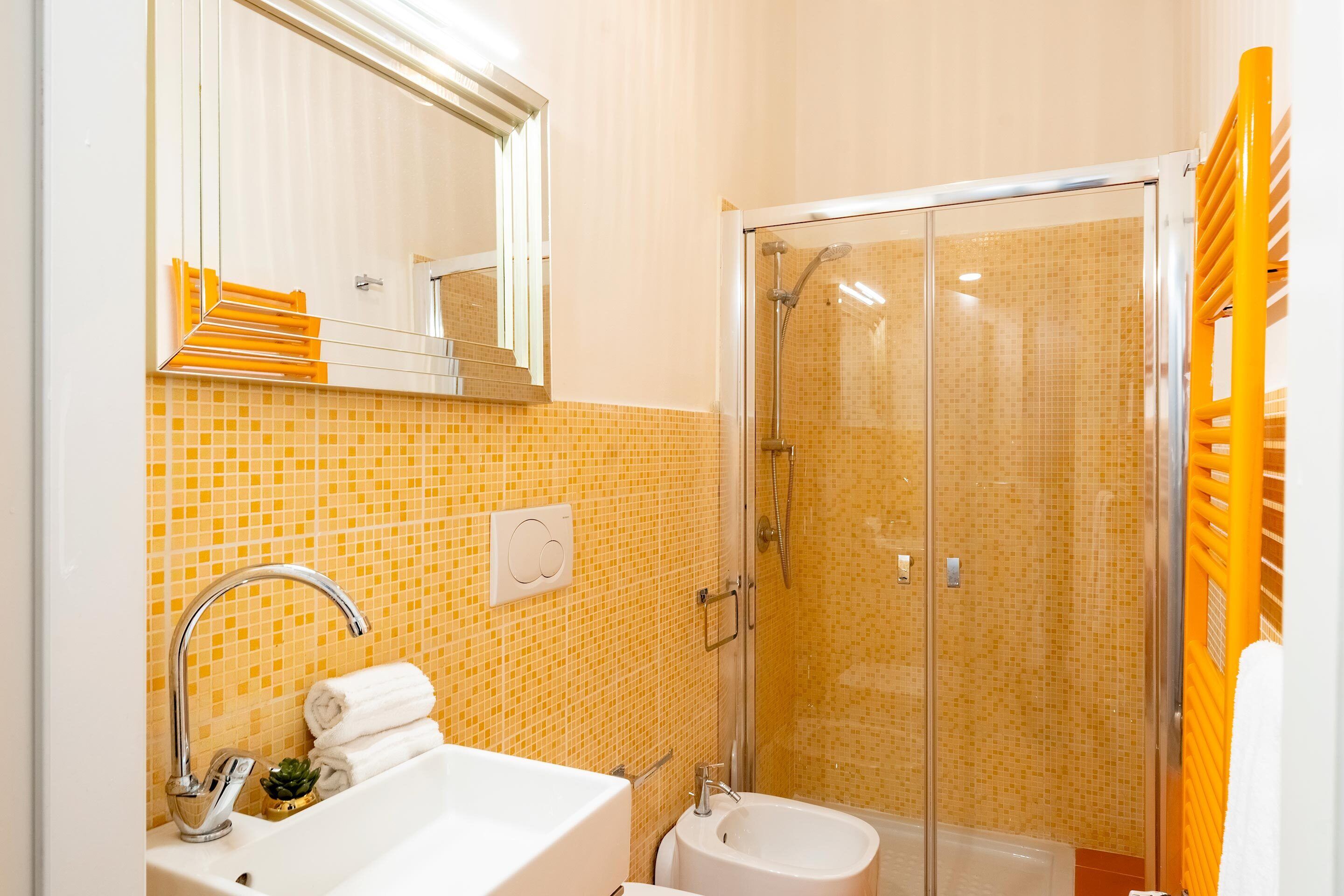 A bathroom with a sink, mirror, and shower area.