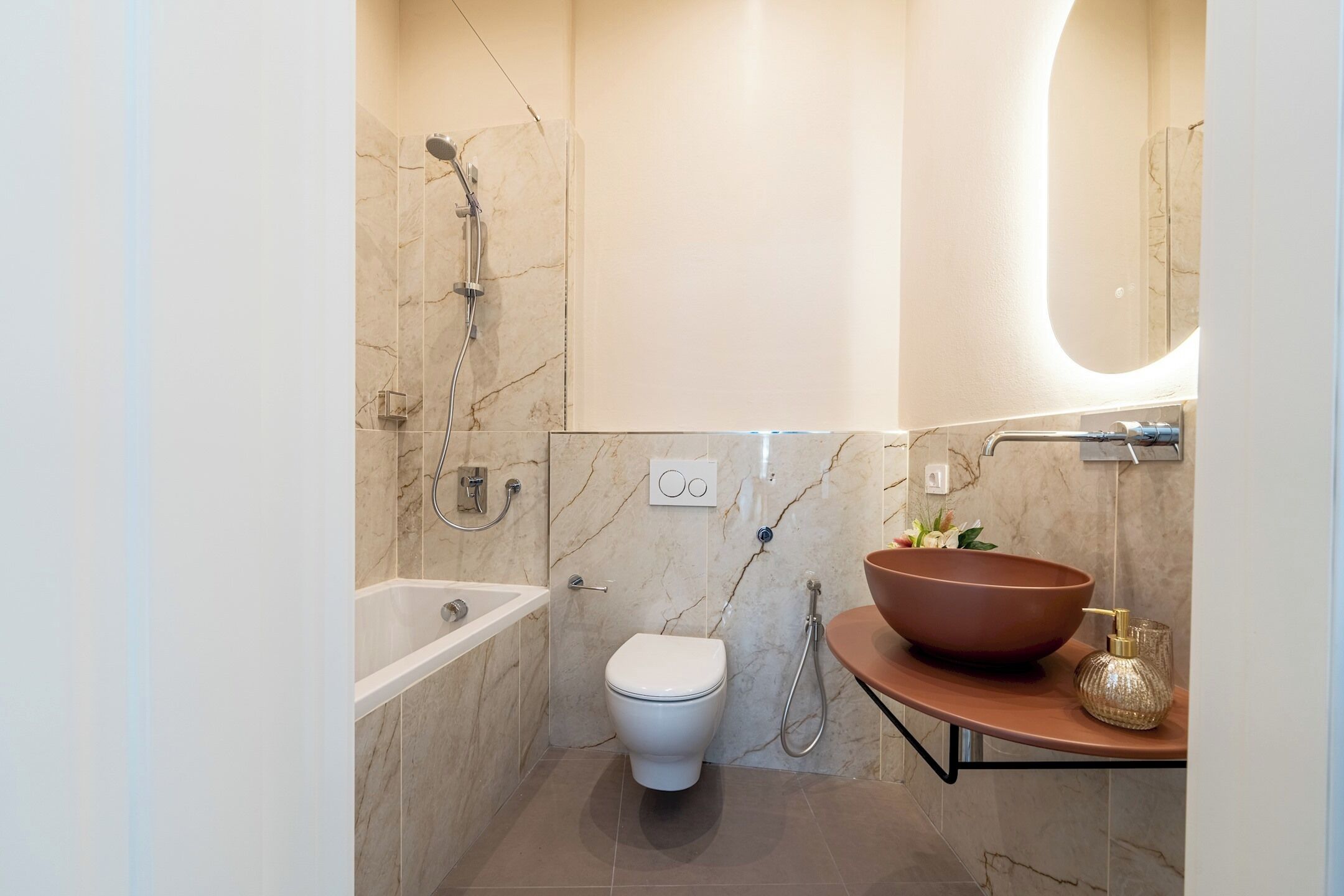 A modern bathroom with a bathtub, toilet, and a large vessel sink.