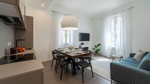 A modern kitchen with a dining area, a flat-screen TV, and a sofa. - Genteel Home Cittadella (Florence)