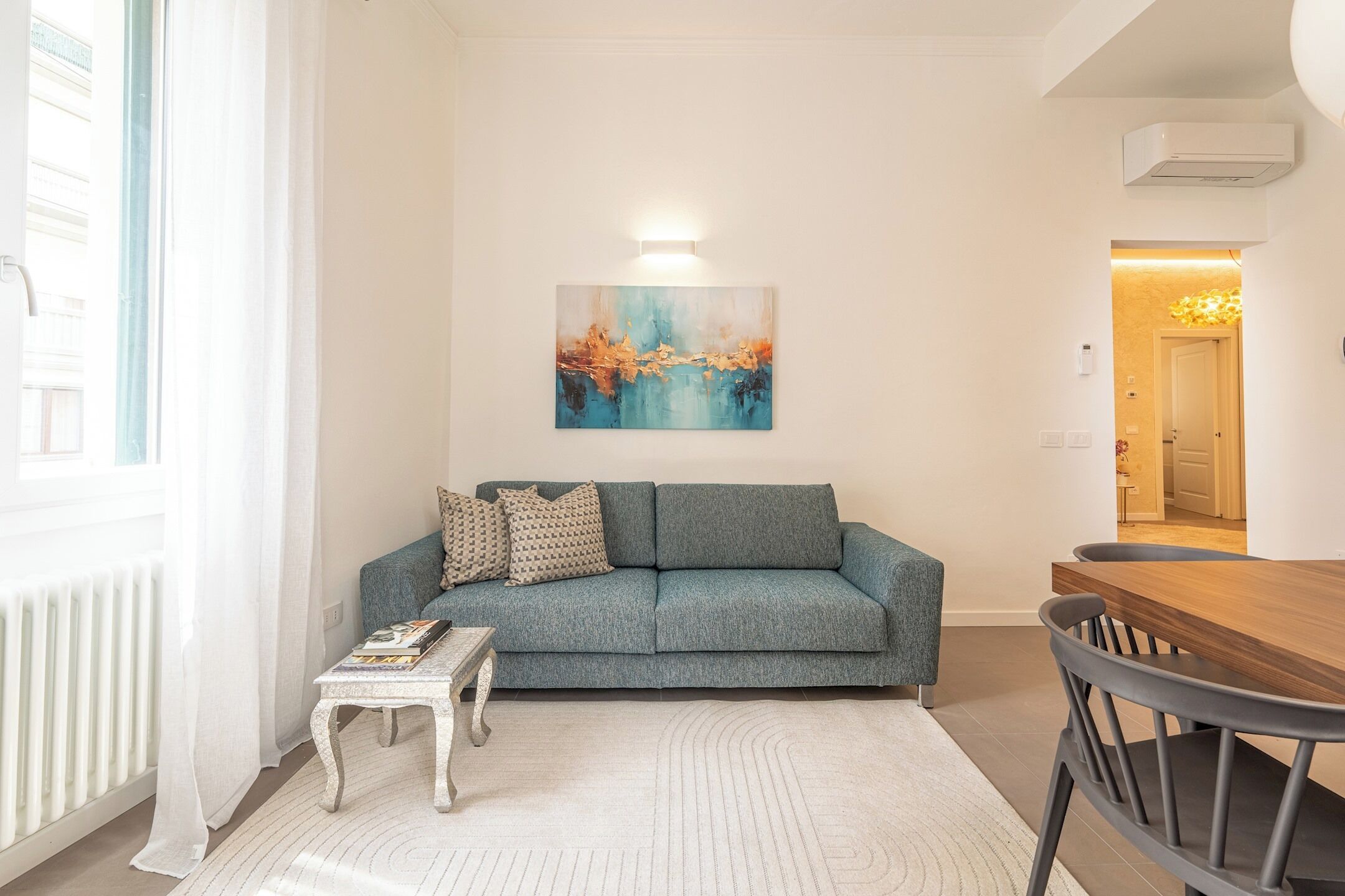 A living room with a grey sofa, a coffee table, and a painting on the wall.
