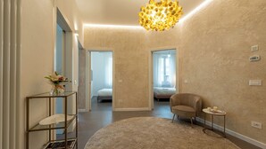 A modern room with a round carpet, a glass shelving unit, a decorative light fixture, and a sofa. - Genteel Home Cittadella (Florence)