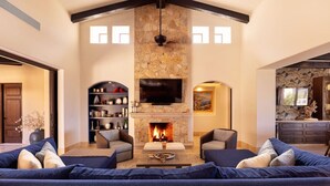 Una sala de estar con chimenea de piedra, un televisor grande y un rincón de descanso acogedor.