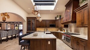 Una cocina amplia con armarios de madera oscura, una isla central y electrodomésticos modernos.