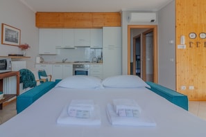 A hotel room with a bed, a kitchenette, and a wooden wall. - Panorama del Lago in Perledo (Perledo)