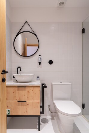 Ein modernes Badezimmer mit einem weißen Waschbecken, einer Holz-Kommode und einer Toilette.