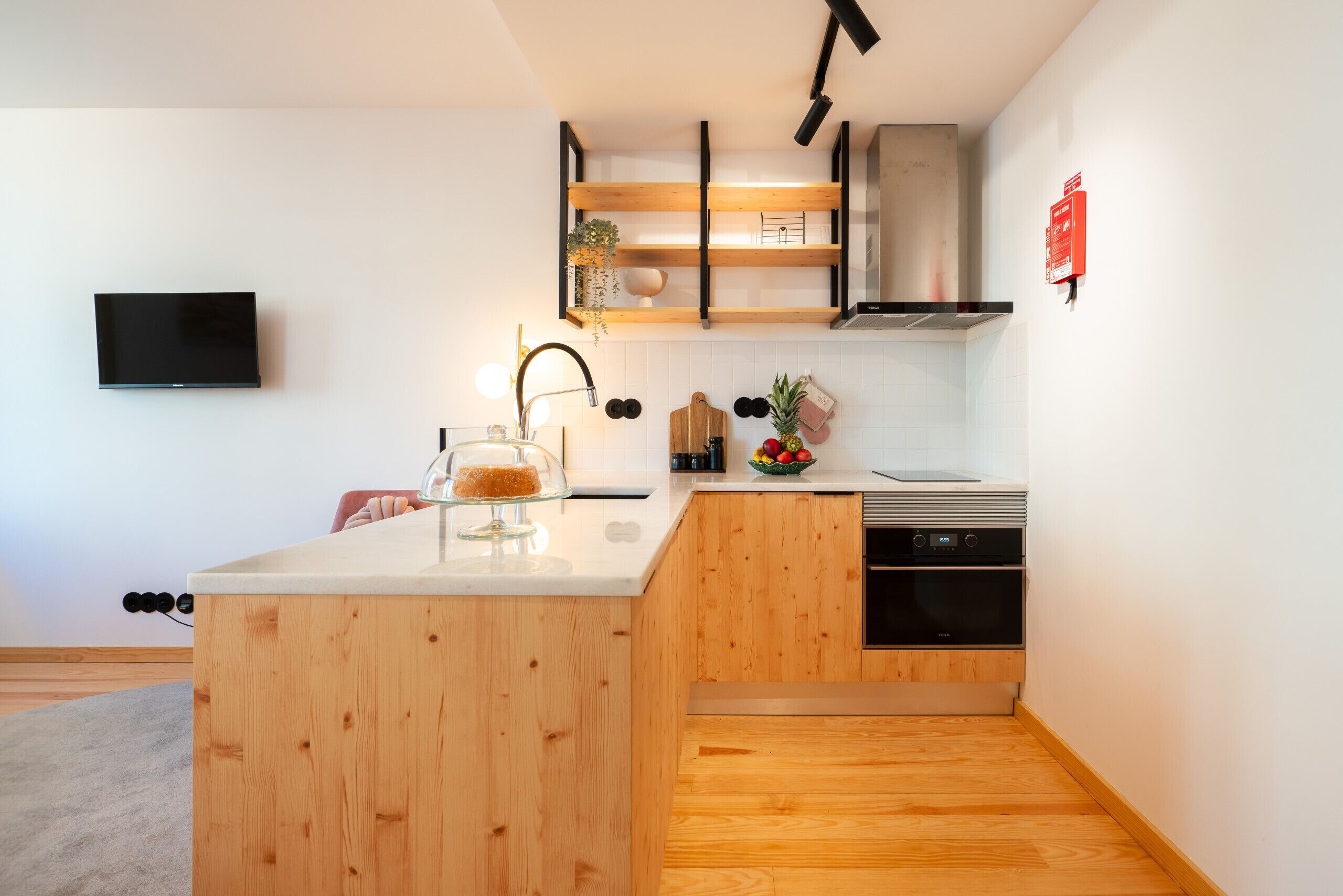 Una cocina moderna con armarios de madera, horno empotrado y una pequeña isla con vitrina de vidrio.