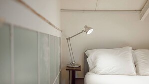 A bedroom with a bed, white bedding, a bedside table, and a desk lamp. - Clerigos Loft by Hosty (Oporto)