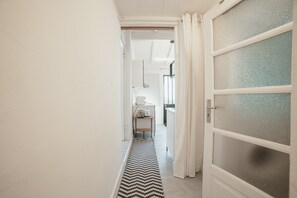 A narrow hallway with a zigzag rug leading to a kitchen area. - Clerigos Loft by Hosty (Oporto)